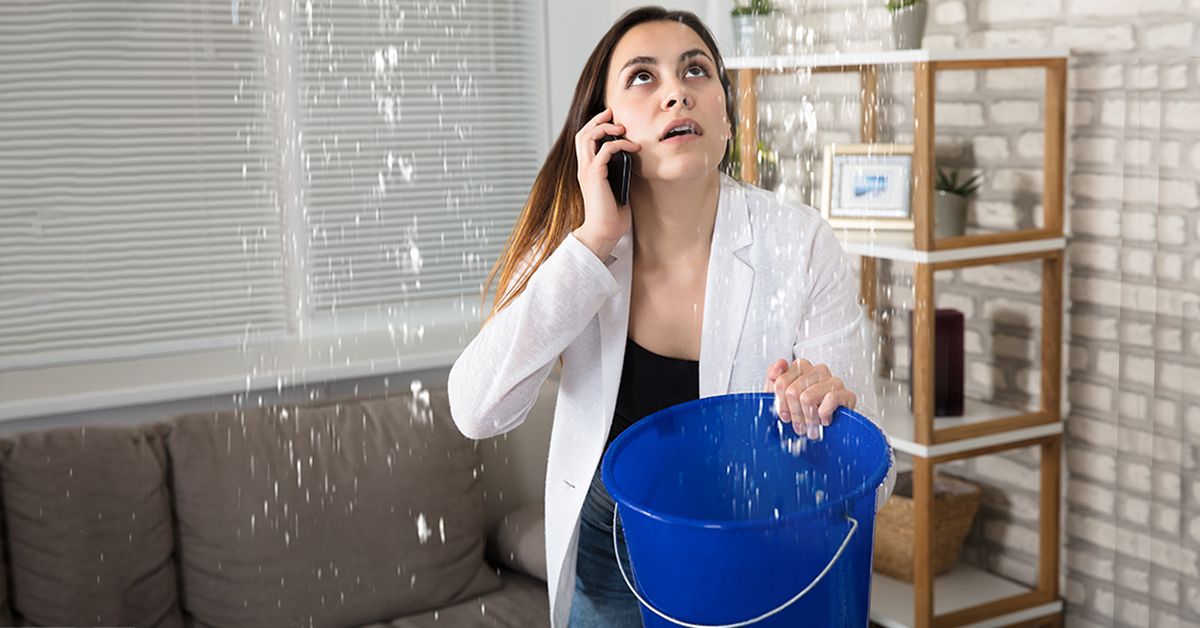 Girl-using-blue-bucket-to-collect-water-dripping-from-the-ceilings
