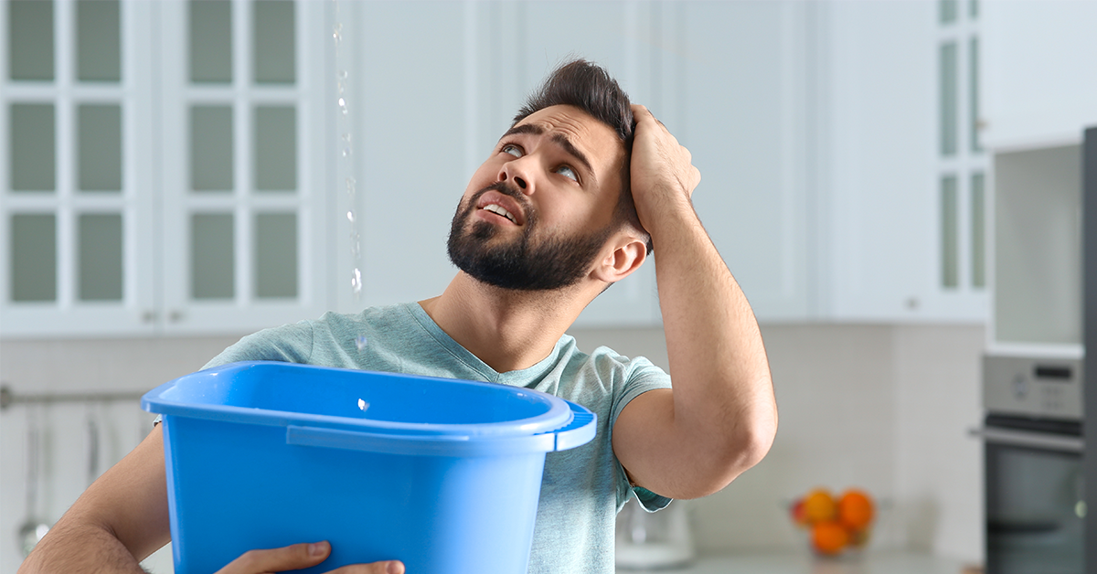 Man-looking-troubled-by-water-leakage-from-ceiling-of-home